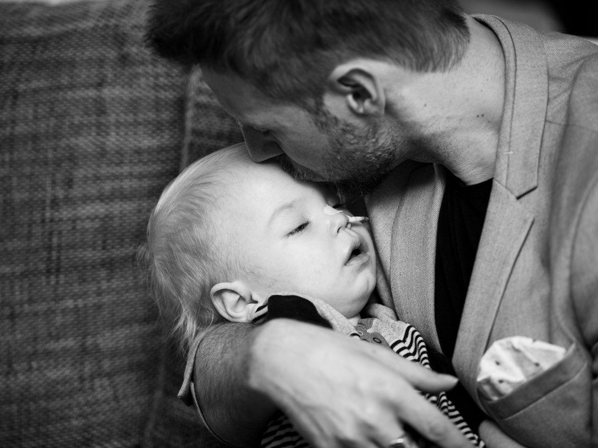 Oče drži bolnega dojenčka — črno-bela fotografija